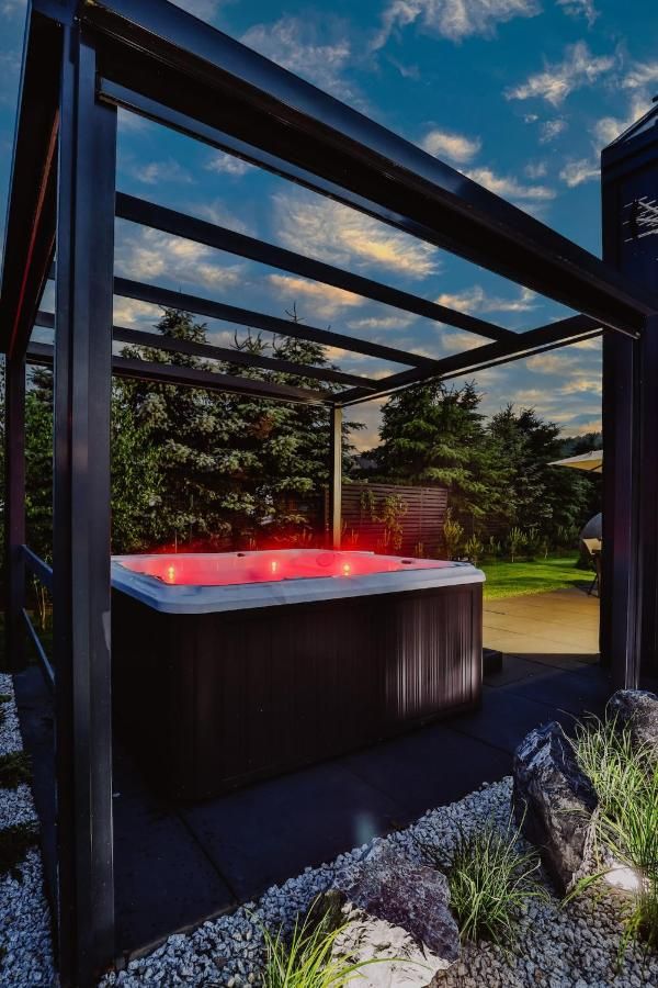 Podświetlone na czerwono jacuzzi przy zadaszonym tarasie